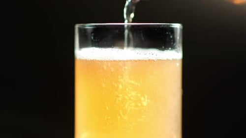 Muitas bolhas de ar subindo em espuma de bebida alcoólica. Câmera lenta, isolada no fundo preto do estúdio