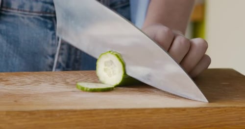 Close Up of Woman Slicing Fresh Cucumber on Cutting Board