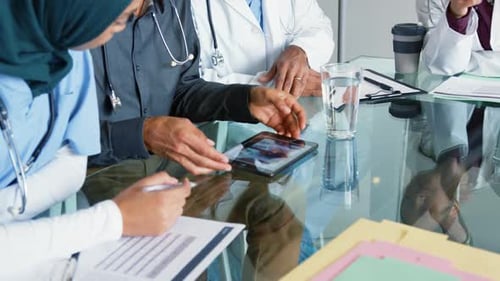 Medical Professionals Reviewing X-Ray on Tablet in Meeting