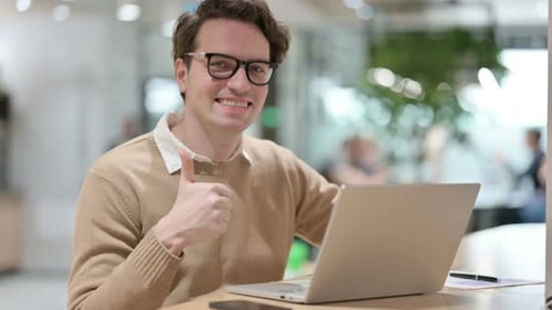 Man Working on Laptop Gives Thumbs Up