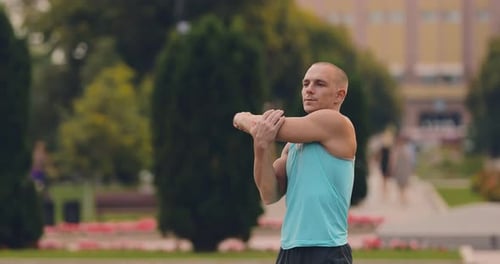 Man Stretching Arms Before Workout in Urban Park
