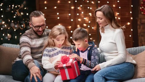 Adorable Family Opening Fairytale Wrapped Red Xmas Gift Box Together