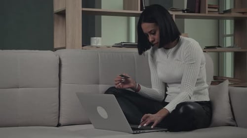 Woman on Couch Uses Laptop and Credit Card