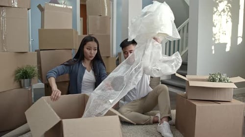 Young Couple Unpacking Lamp in New Home