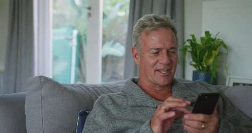 Smiling Adult Answering Phone on Couch