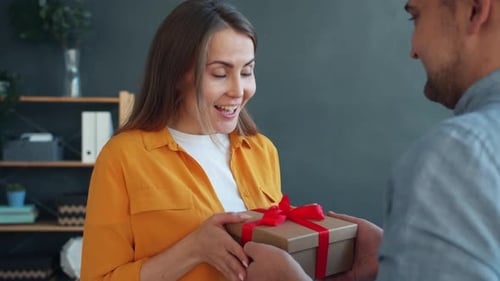 Loving Man Congratulating Woman Giving Gift Box Hugging Expressing Love at Home
