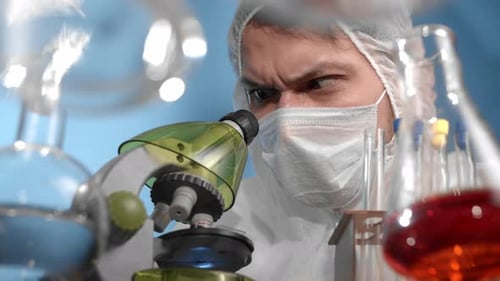Scientist Looks Through Microscope in Laboratory Close Up