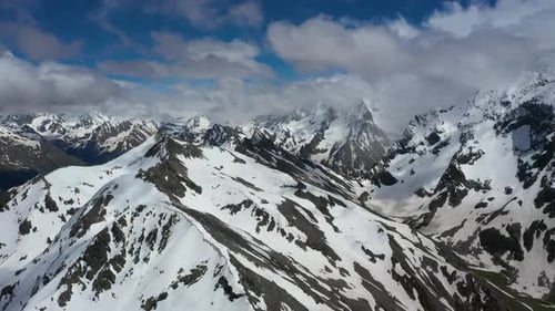 Air Flight Through Mountain Clouds Over Beautiful Snowcapped Peaks of Mountains and Glaciers