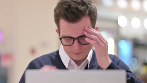 Young Adult With Headache Working on Laptop