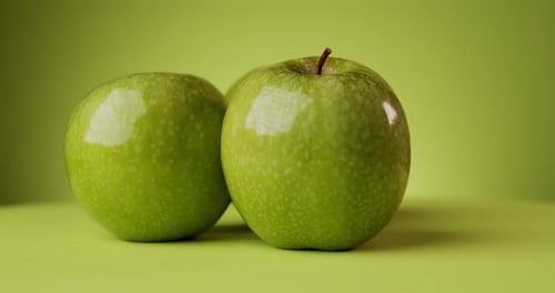 Köstliche rotierende grüne Äpfel auf farbigem Hintergrund