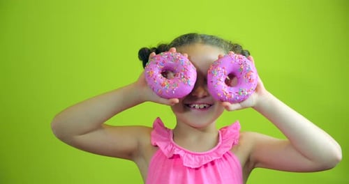Portrait Child Attractive Little Girl Holding Donuts with Icing To Her Hands Smiling Looks at the