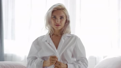 Woman Buttons Up Shirt and Smiles at Camera