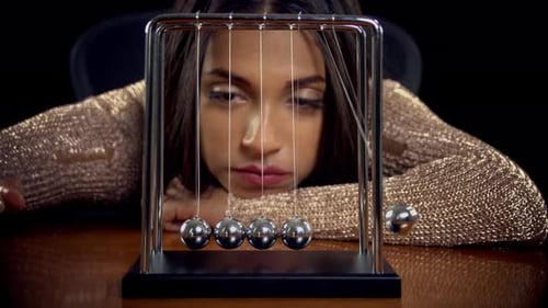 Woman Watches Newton's Cradle Kinetic Energy Transfer