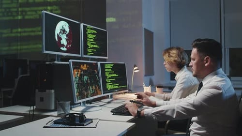 Two Workers Coding at Computers Late at Night