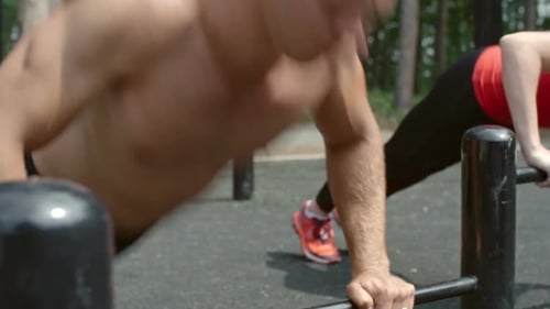 Two People Exercising on Parallel Bars Outdoors