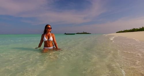 Young smiling lady on holiday by the sea on the beach on summer white sand and blue 4K background