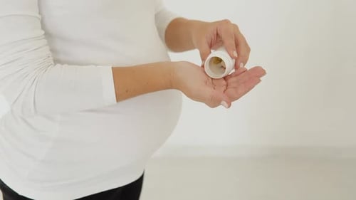 Pregnant Woman Pouring Pills Into Her Hand