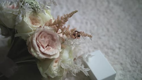 Wedding Rings Lie Near Beautiful Wedding Bouquet on the White Floor