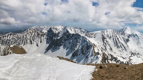 Wide View of Snowy Mountain Peaks on Cloudy Day