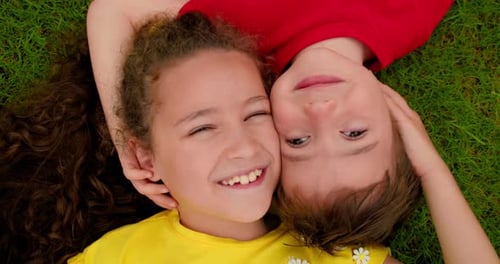 Happy Little Brother and Sister Lies on Green Grass