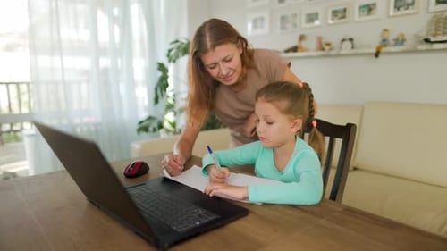 Woman Helps Girl with Schoolwork at Home