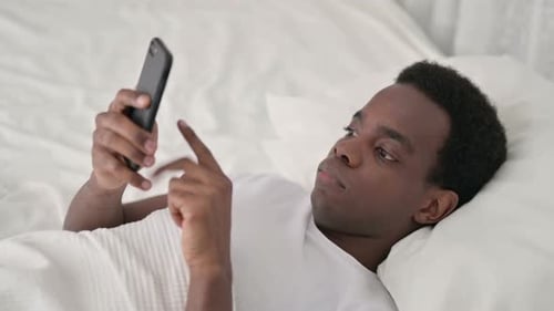 Man Lying in Bed Using Mobile Phone