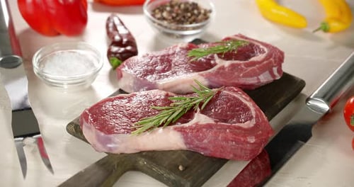 Raw Beef Steaks on Cutting Board with Rosemary