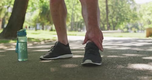 Low section of man holding his leg in the park