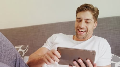 Man Relaxing in Bed Using Tablet