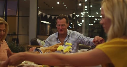 Family and Friends Gathered Holding Hands at Dinner