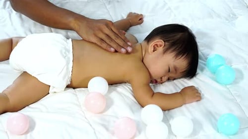 bebé durmiendo en una cama con palmaditas en las manos