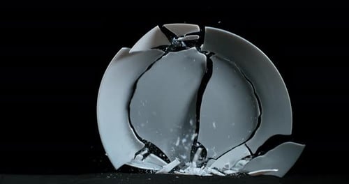 Platte fällt und explodiert auf schwarzem Hintergrund, Zeitlupe 4K