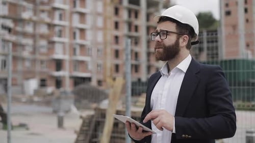 Architekt im Geschäftsanzug steht mit Tablet auf der Baustelle und analysiert