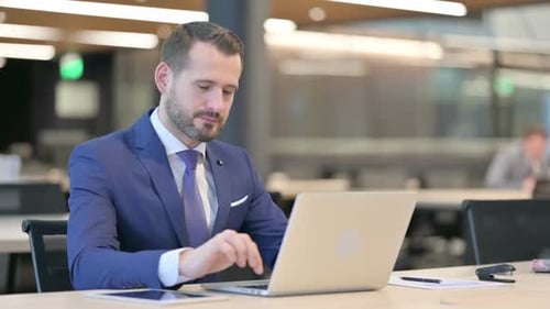 Man at Desk Gives Thumbs Up in Office