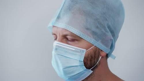 Un médecin regarde dans le cadre avec des yeux fatigués en larmes en pleurant après un passage fatigant au traitement