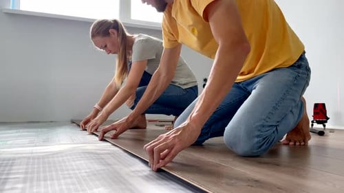 Couple Installing Laminate Flooring Together Indoors