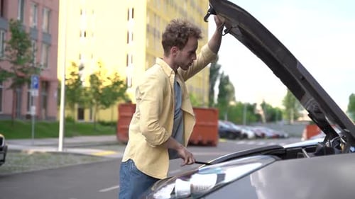Guy in the middle of the street opened the hood of his car.
