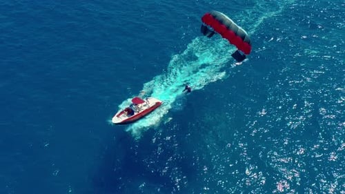 Aerial View. Flying with Parachute Behind a Boat. Extreme Water Sport in the Sea. Parasailing.