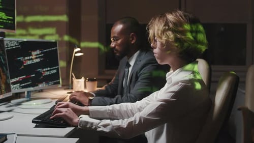Two Colleagues Work at Computers Late at Night