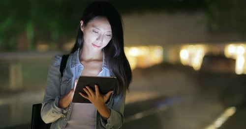 Woman Using Tablet at Night in City
