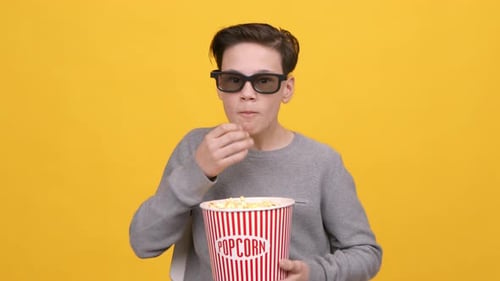 Boy Wearing 3DGlasses Watching Movie And Eating Popcorn Yellow Background