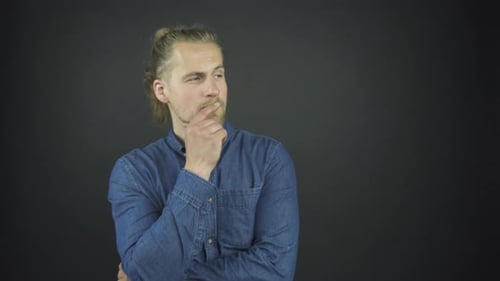 Handsome Bearded Guy with Ponytail Touches Face with Hand