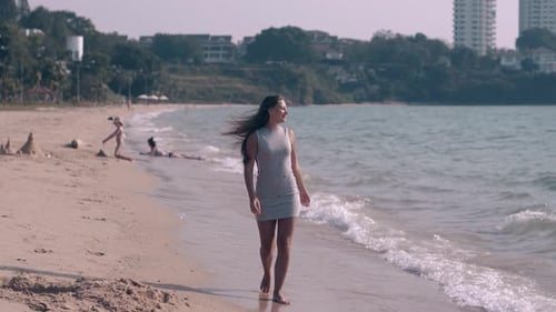 Girl with Long Hair Walks on Wet Beach Sand By Ocean Waves