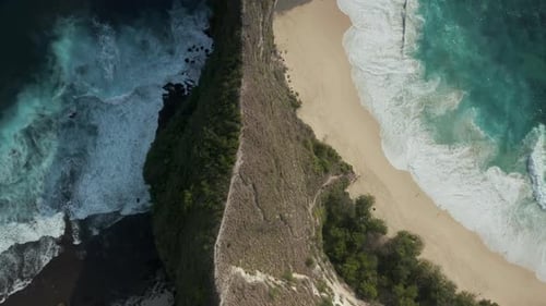 Aerial view of a sandy beach, rough sea and dramatic cliffs