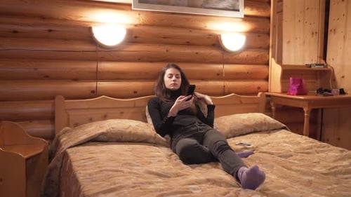 Woman Watches Television in Cozy Cabin Bedroom