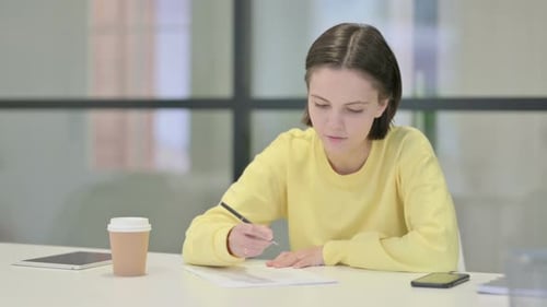 Young Woman Writing on Paper in Office