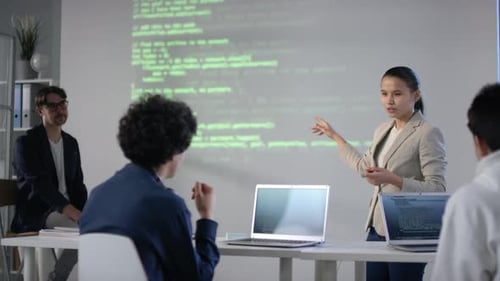 Woman Presenting Code to Colleagues in Office
