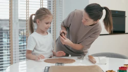 Daughter helps mother baking cookies
