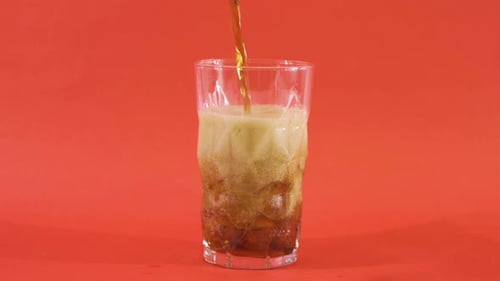 Pouring Soda Into a Glass With Ice
