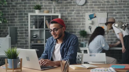 Cheerful Young Man Using Laptop Typing Working in Modern Loft Style Office